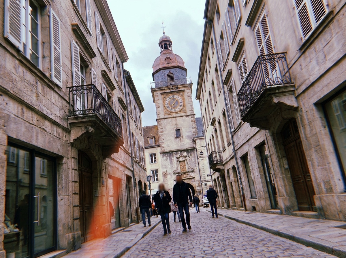 Historic clock tower framed at the end of an old city street